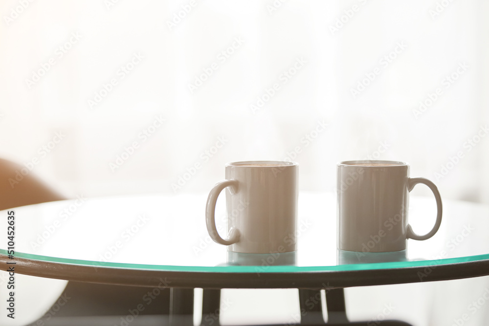 Fototapeta premium two cups of coffee on a glass table.