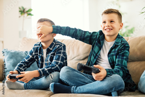 child brother friend having fun playing console laughing happy kid controller gaming