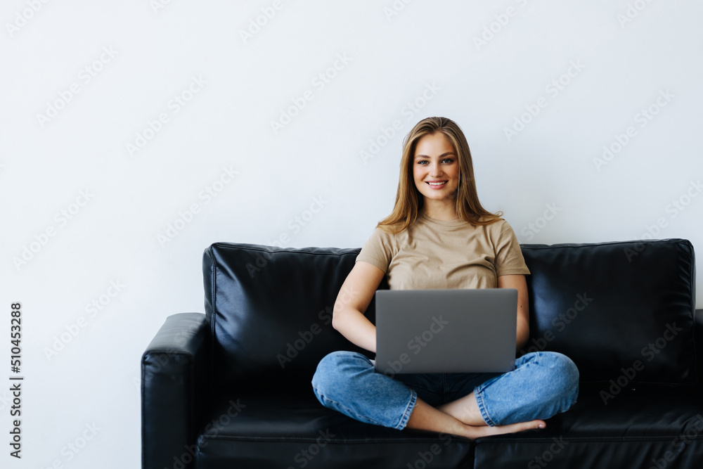 Young woman working on laptop sit on sofa in apartment Young woman working on laptop sit on sofa in apartment