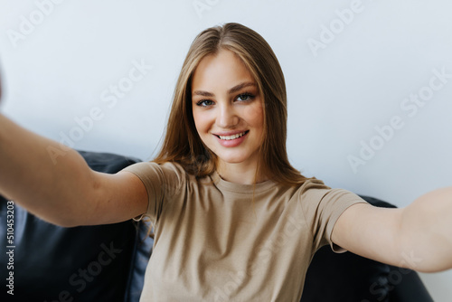 Portrait of beautiful woman taking a self-portrait with her smartphone at home.