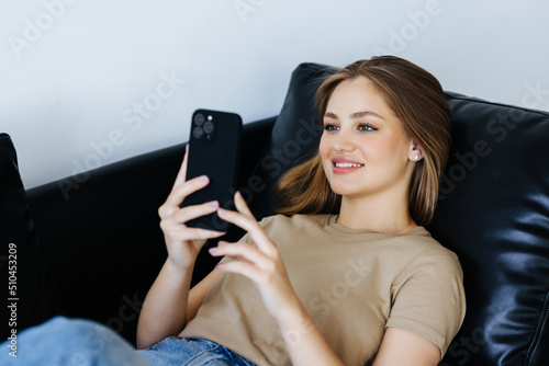 Joyful brunette nice girl smiling use mobile phone on sofa at home