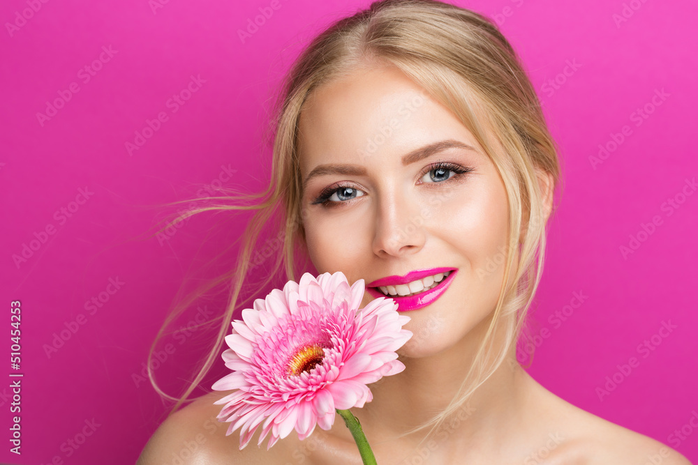 Beauty Model with Pink Lipstick. Smiling Young Woman with Smooth Skin Makeup and Lip Gloss. Fashion Girl Portrait with Glossy Lipstick with Flower over Purple Background. Women Cosmetics and Facial Ca Beauty Model with Pink Lipstick. Smiling Young Woman with Smooth Skin Makeup and Lip Gloss. Fashion Girl Portrait with Glossy Lipstick with Flower over Purple Background. Women Cosmetics and Facial Ca