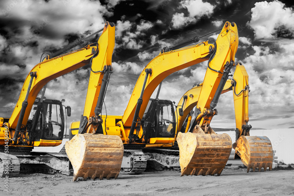 Powerful excavators at a construction site against a cloudy evening sky. earthmoving construction equipment. Lots of excavators.