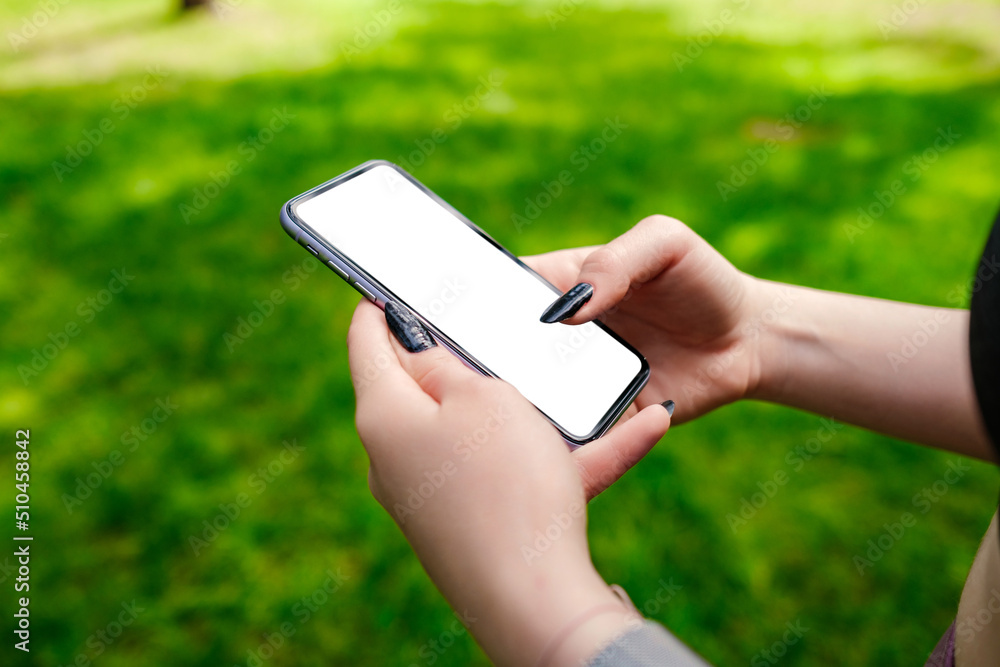 Beautiful brunette woman wearing sports bra standing on city park, outdoors hands holding phone touching finger mockup white blank display, mobile application tech concept.