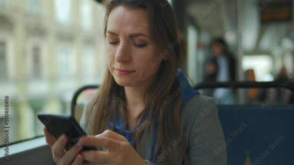 Woman in tram using smartphone chatting and texting with friends. City, urban, transportation. Woman in tram using smartphone chatting and texting with friends. City, urban, transportation.