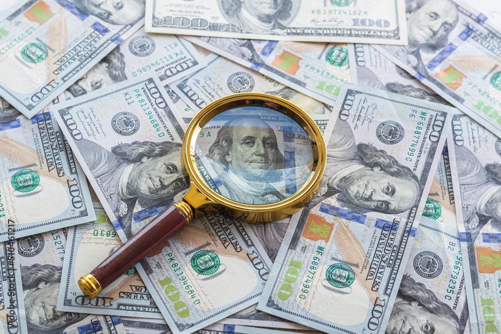 one hundred dollars. a magnifying glass in a gold frame. close-up one hundred dollars. a magnifying glass in a gold frame. close-up