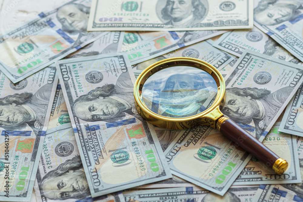 one hundred dollars. a magnifying glass in a gold frame. close-up one hundred dollars. a magnifying glass in a gold frame. close-up