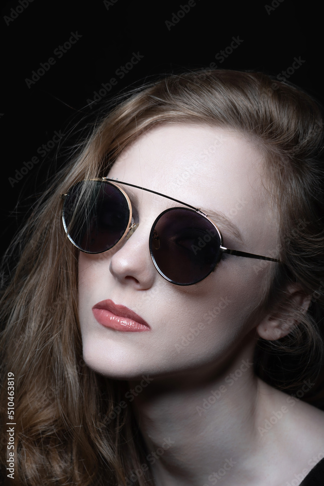 Beauty, style, make-up and fashion concept. Beautiful woman with round retro sunglasses and long wavy brown hair close-up studio portrait. model with pink lipstick and bare neck looking aside a camera Beauty, style, make-up and fashion concept. Beautiful woman with round retro sunglasses and long wavy brown hair close-up studio portrait. model with pink lipstick and bare neck looking aside a camera