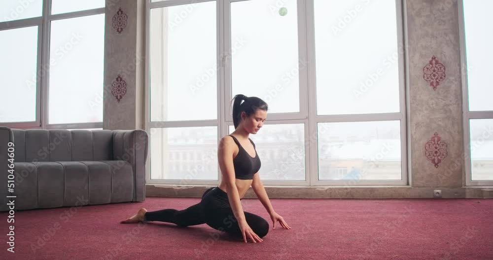 Side view of slim girl with ponytail sitting on twine, bending, stretching, lying down on red carpet. Pretty, brunette female practicing yoga pose. Concept of modern life. Side view of slim girl with ponytail sitting on twine, bending, stretching, lying down on red carpet. Pretty, brunette female practicing yoga pose. Concept of modern life.