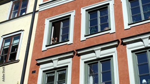 Two feet up emerge from a window in the historic center during a sunny morning.
