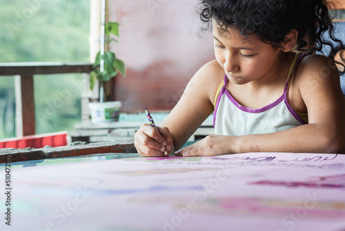 close-up of a brown-skinned latina girl, coloring her homework with a purple pencil, low-income colombian student concentrating on her drawing. concept of poverty and nature
