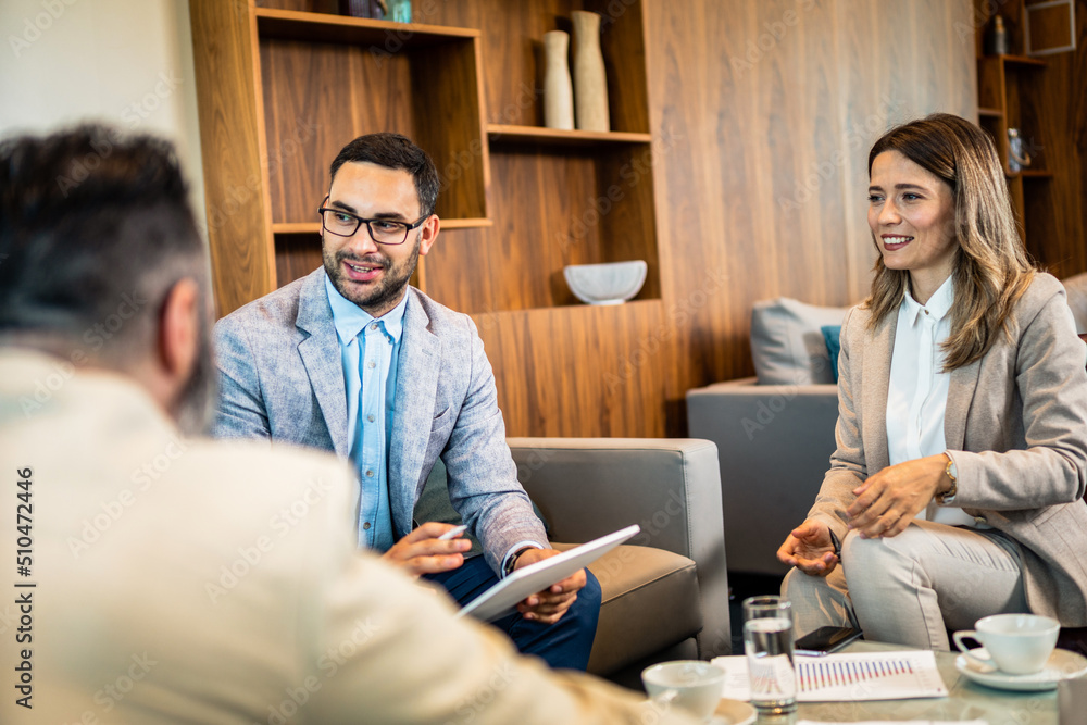 Fototapeta premium Teamwork. Team discussing something and smiling while sitting at the modern business lounge.