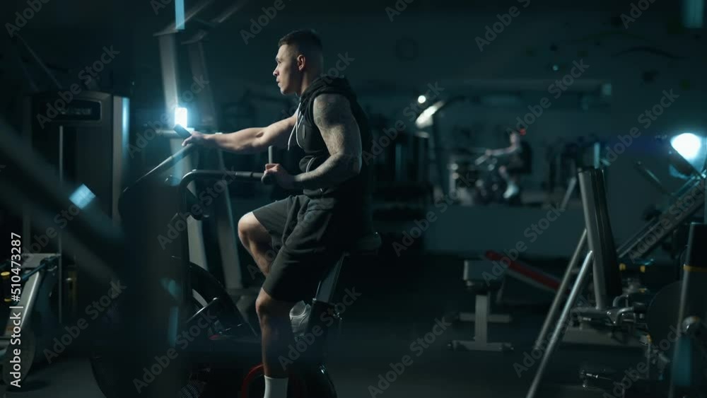 A handsome young muscular sportsman is doing exercise on a fitness machine in the gym. Concept of lifestyle fitness health and sports. Maximum focus and strength. A handsome young muscular sportsman is doing exercise on a fitness machine in the gym. Concept of lifestyle fitness health and sports. Maximum focus and strength.