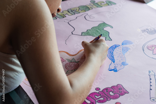 young latin woman making a poster about the colombian amazon region. studying about the culture and richness of the prehispanic and precolumbian indian people. drawing about the amazonian gastronomy. photo