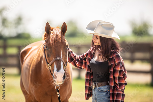 Beautiful girl strokes a horse smiling at it in a farm