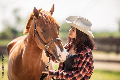 Brown horse leans towards a cowgirl on a ranch before horseriding