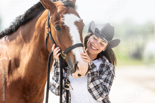 Woman with passion for horses holds and strokes the nose of a horse standing close to it
