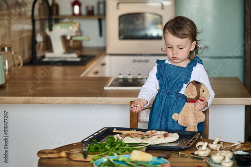 A little cute child cook pizza in the kitchen. The concept of a happy family