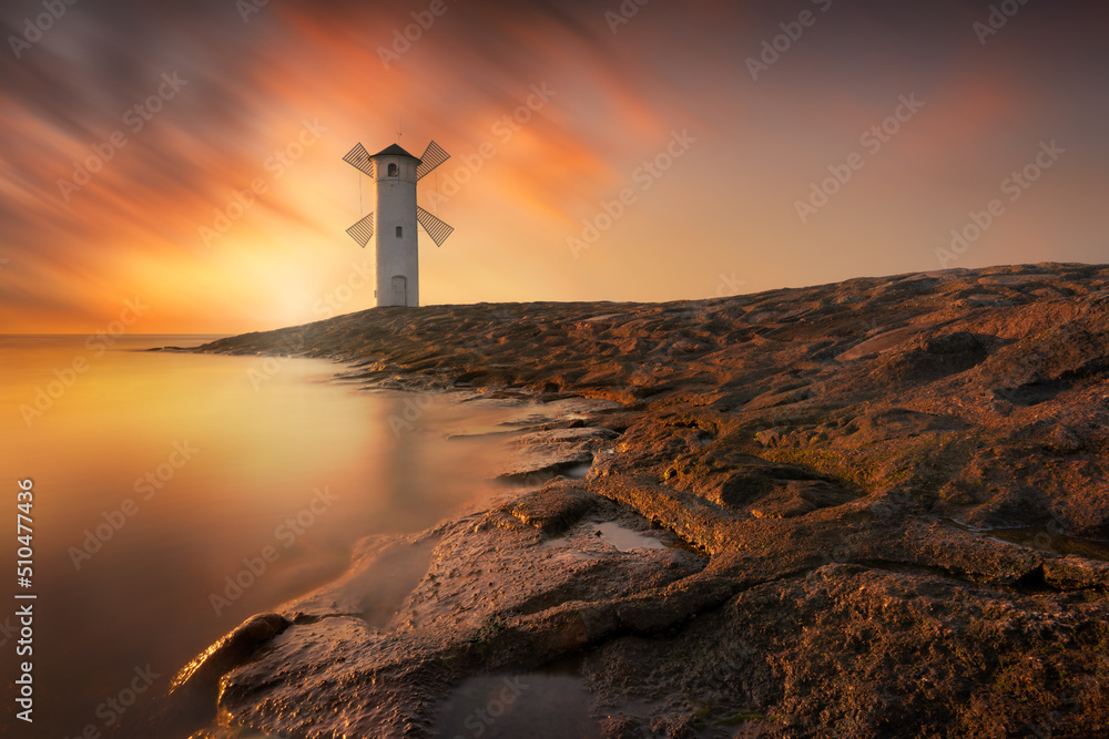 Pond Mlyny - a windmill pond by the sea in Swinoujscie, Poland. A white mill by the sea with a beautiful sunset. Sea sunset landscape.