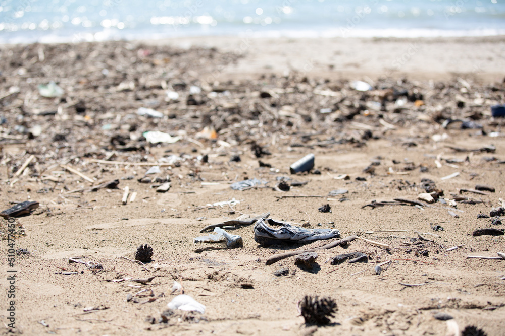 Fototapeta premium Environmental pollution, beached garbage and old shoes