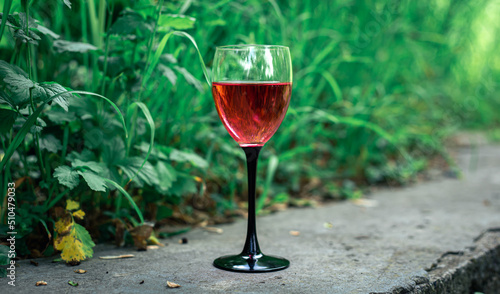 A glass of red wine on a blurred grass background.