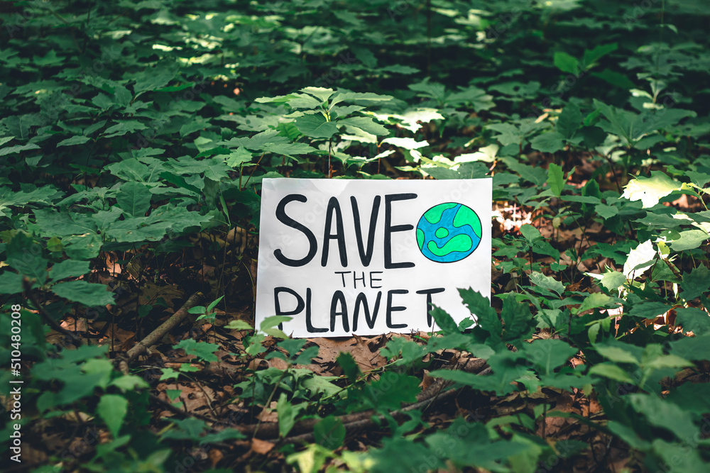 Poster with the inscription save the planet in the forest among the plants.