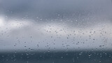 gotas de chuva no vidro com nuvens escuras desfocadas