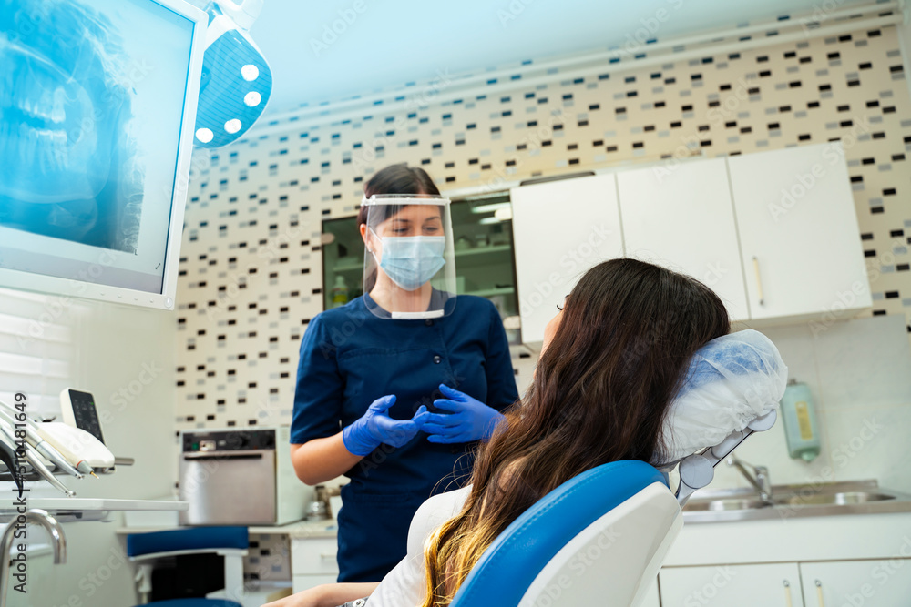 Woman dentist fully protected talking with patient Woman dentist fully protected talking with patient