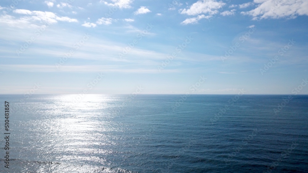 aerial view over calm sea to the horizon which reflects the sun, partly cloudy sky, high quality image aerial view over calm sea to the horizon which reflects the sun, partly cloudy sky, high quality image