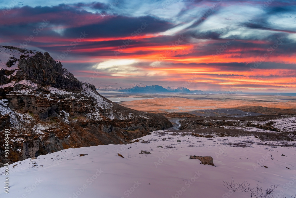Scenic view of rocky cliffs on snow covered landscape. Beautiful view of volcanic valley against cloudy sky. Idyllic scenery of Icelandic nature in winter during sunset. Scenic view of rocky cliffs on snow covered landscape. Beautiful view of volcanic valley against cloudy sky. Idyllic scenery of Icelandic nature in winter during sunset.