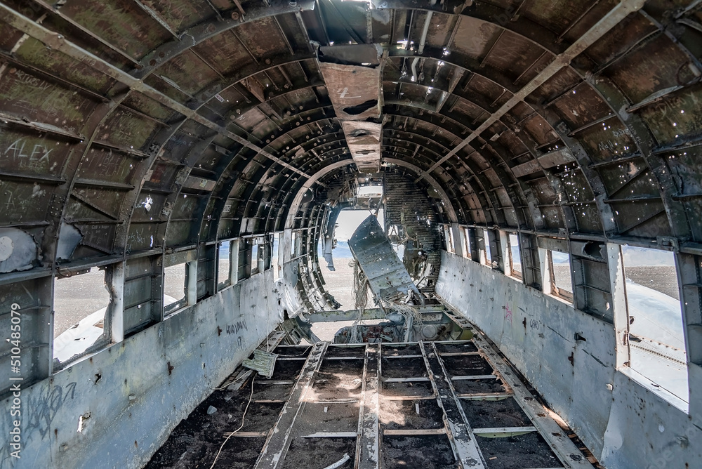 Interior of crashed military airplane wreck. Abandoned broken metallic aircraft at black sand beach. Famous tourist attraction in Solheimasandur on volcanic landscape.