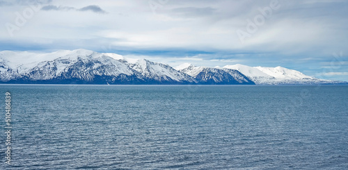 Scenic view of seascape and snowcapped mountains. Beautiful view of Atlantic ocean against cloudy sky. Idyllic scenery of sea and volcanic range during winter. © Aerial Film Studio