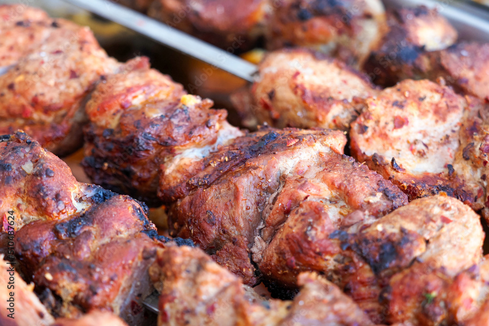 Barbecue is cooked on the coals. Pieces of meat on skewers in barbecue, closeup. Kebab