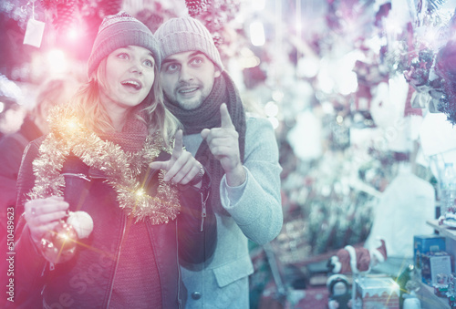 Positive young couple buying decoration at Christmas Fair outdoor