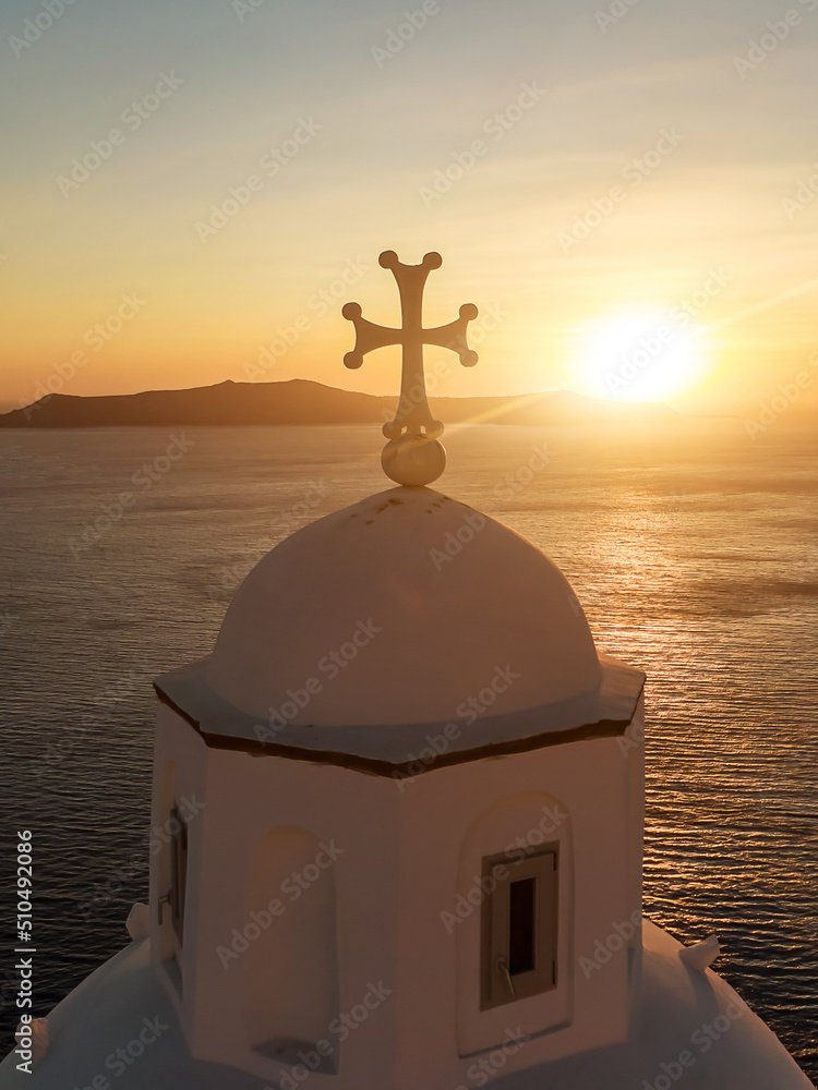 Cross of the Greek white church during sunset.