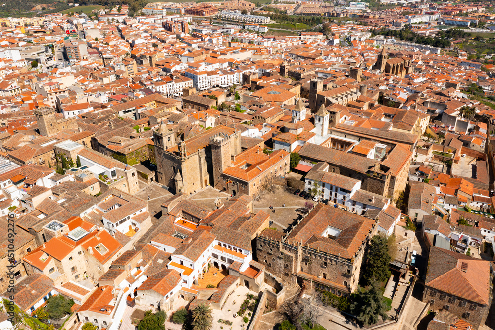 Scenic aerial view of ancient quarter of Spanish city of Caceres overlooking brownish tiled roofs of old buildings and temples on sunny spring day, Extremadura..