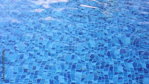 Água de piscina com pequenas ondas. Água em movimento em uma piscina de vinil com mosaico cheio de quadrados em diferentes tons de cor azul. photo