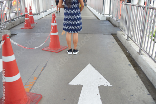 Woman standing on arrow sign near by cones on the footpath