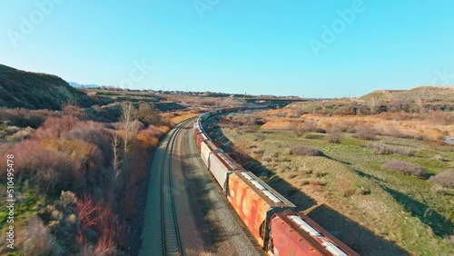 AERIAL - Train on railroad tracks under a blue sky close to Bluffdale, Utah, forward photo