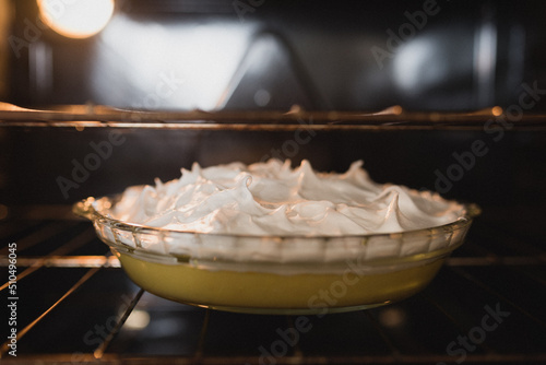 Lemon meringue pie sitting on the oven rack inside the oven; freshly baked