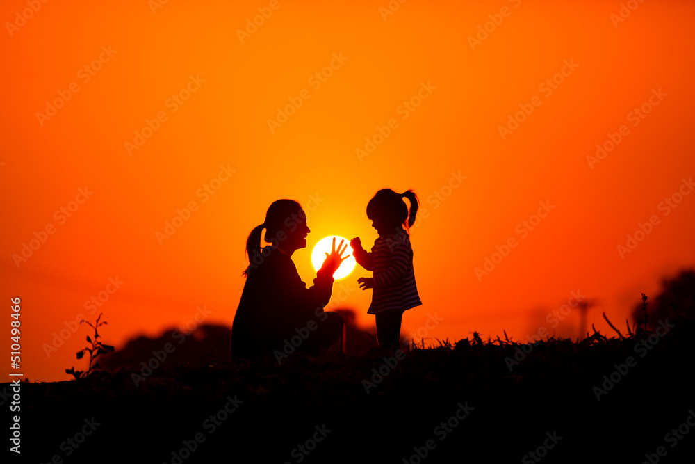 Mother and child play together before the sun in the sunset