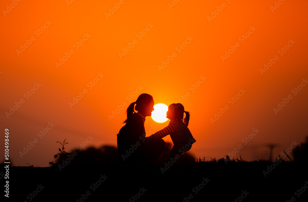 Mother and child play together before the sun in the sunset