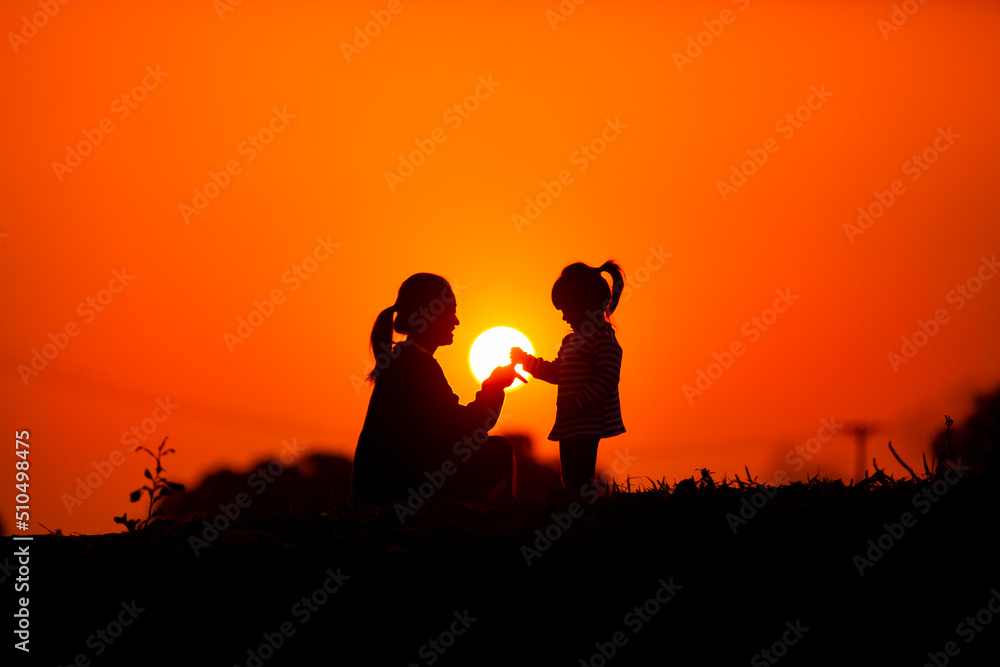 Mother and child play together before the sun in the sunset