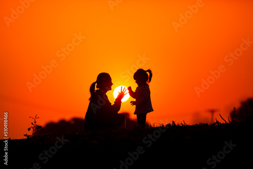 Mother and child play together before the sun in the sunset