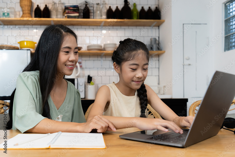 Family and home school concept. Asian mother teach her daughter using application on laptop at home. Family and home school concept. Asian mother teach her daughter using application on laptop at home.