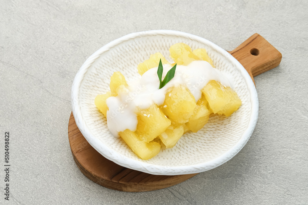 Singkong thailand, sweet cassava, made of boiled cassava, sugar and coconut milk. Served in bowl and pandan leaf, selective focus and blurred background.
