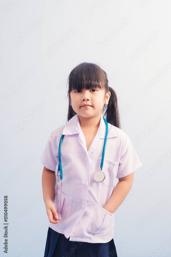 Happy cute girls in white medical uniform and stethoscope act like doctor. child dreams of becoming a doctor career concept Happy cute girls in white medical uniform and stethoscope act like doctor. child dreams of becoming a doctor career concept