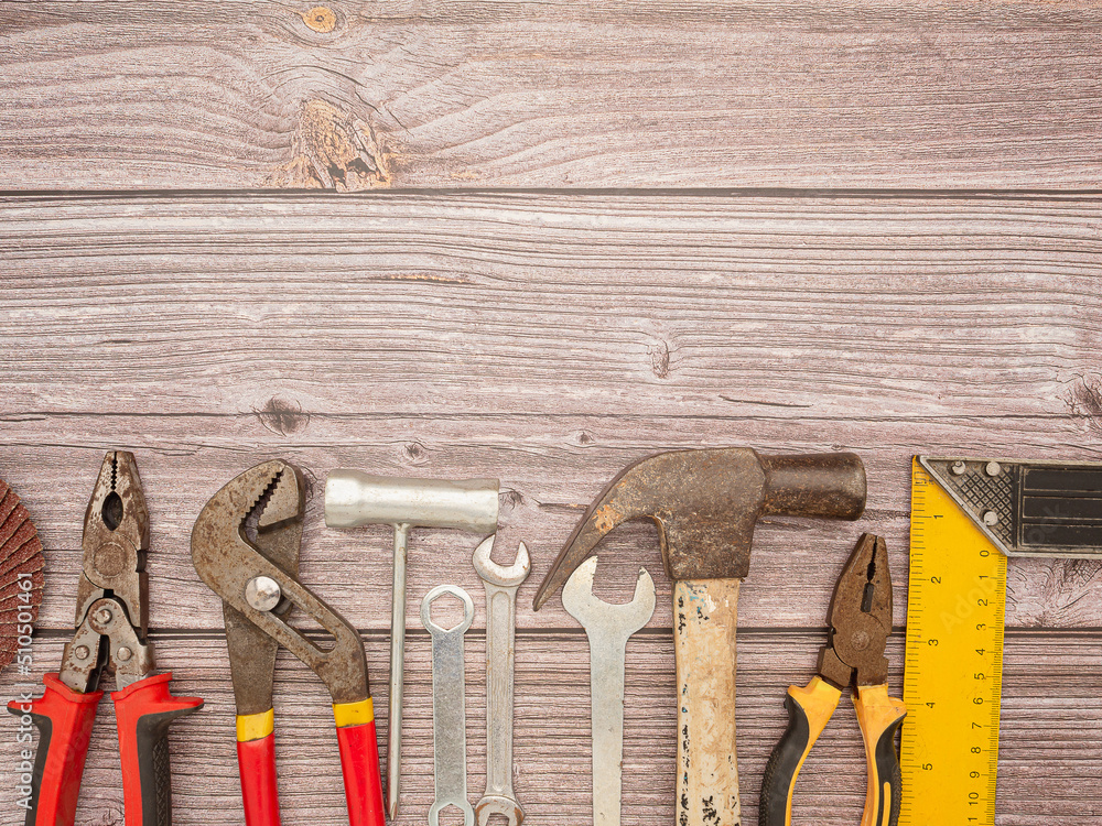 Construction tools, a hammer, screwdriver, screws, and pliers on a wooden table Construction tools, a hammer, screwdriver, screws, and pliers on a wooden table