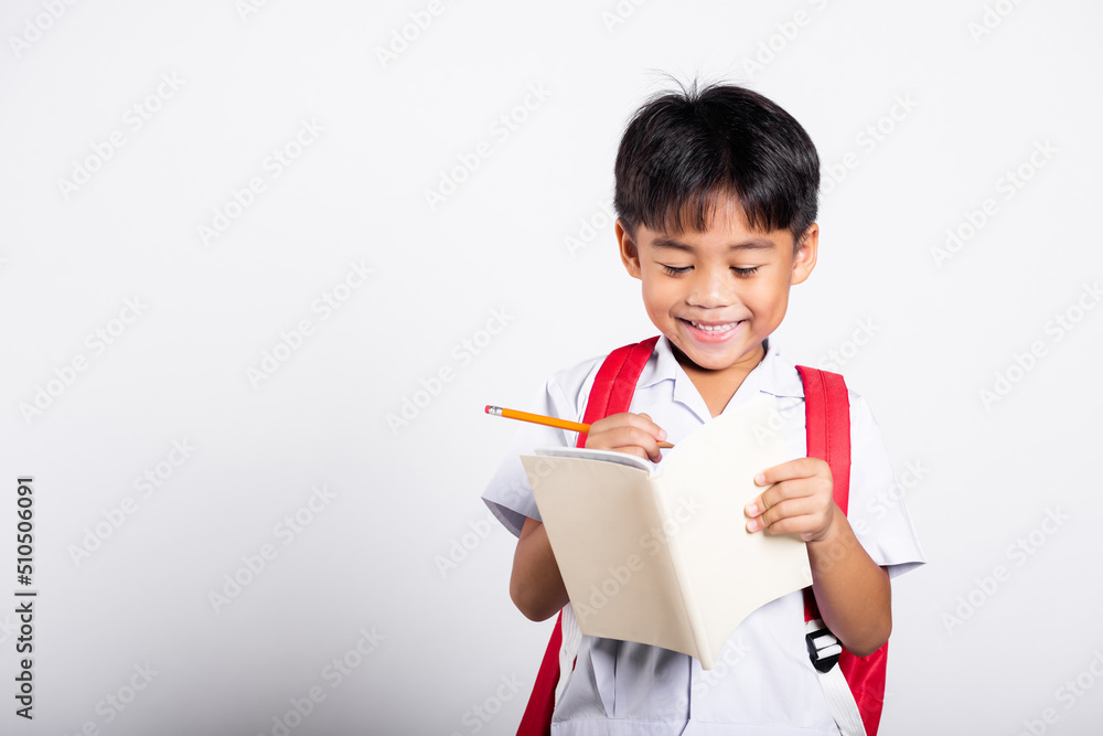 Asian toddler smiling happy wear student thai uniform red pants holding pencil for writers notebook in studio shot isolated on white background, Portrait little children boy preschool, Back to school