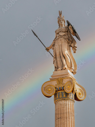 A rainbow over Athena statue, the ancient Greek goddess of wisdom on an Ionic style column at the national academy of Athens, Greece.